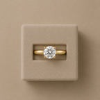 Clarisse solitaire ring set in a beige suede presentation box, photographed from above