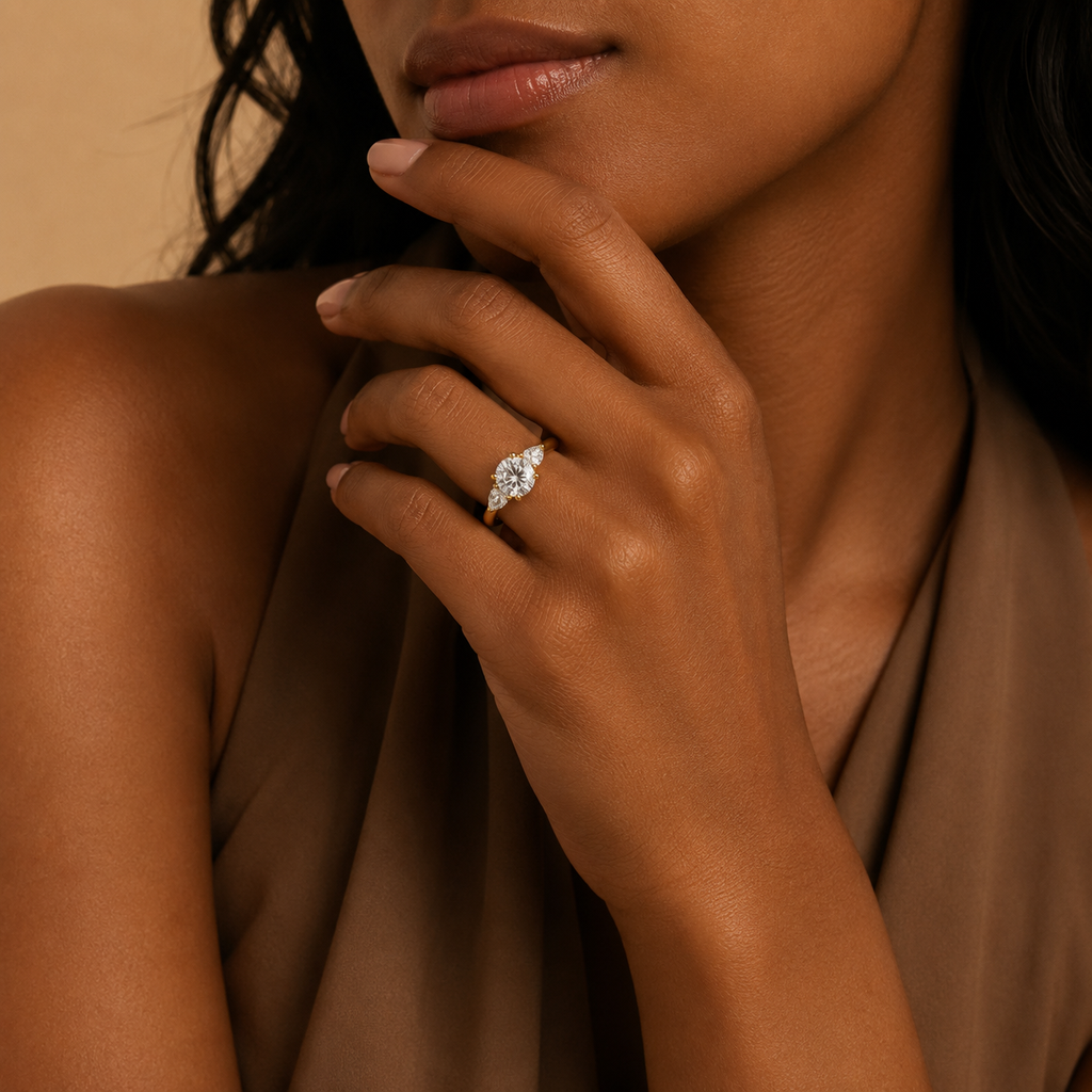 Fleur trilogy engagement ring worn on a model's hand, held up beside the chin