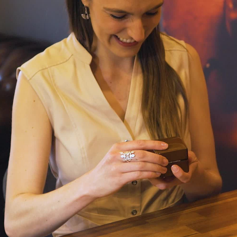 Woman holding a small jewellery box and about to open it.