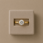 Mariette solitaire ring displayed in a beige suede ring box against a taupe backdrop