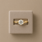 Solara solitaire ring seated in a beige suede presentation box against a taupe background